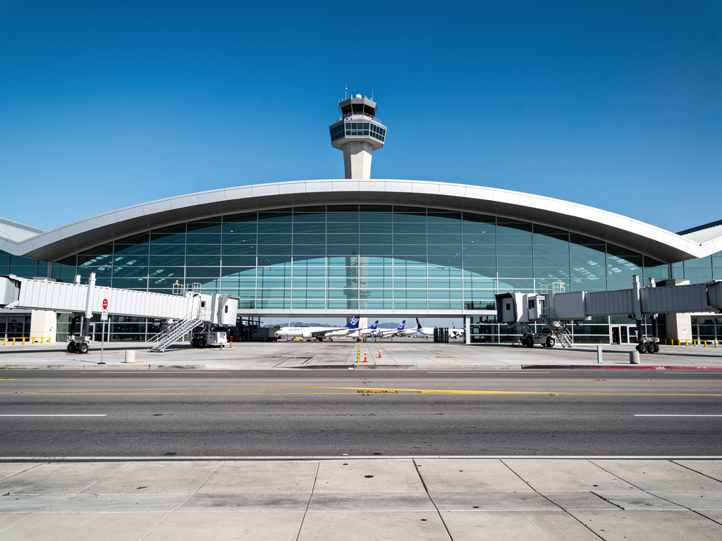 Los Angeles International Airport terminal exterior with modern curved architecture and open air design,

