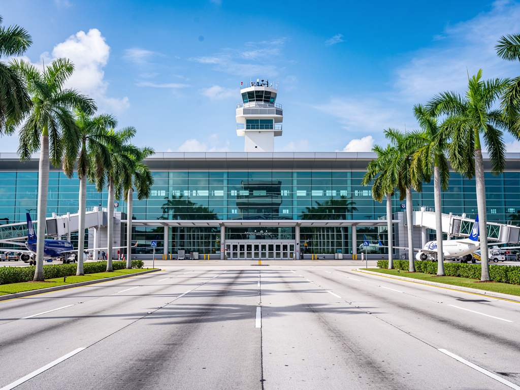 Miami International Airport terminal exterior with palm trees and tropical architecture,
